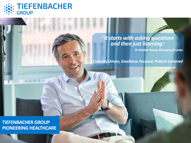 Tiefenbacher Group - A man in a light blue shirt sits and gestures while speaking in a bright office. A quote by Dr. Kristian Ruepp highlights curiosity, excellence, and patient-centric drug development in pharmaceutical healthcare solutions.