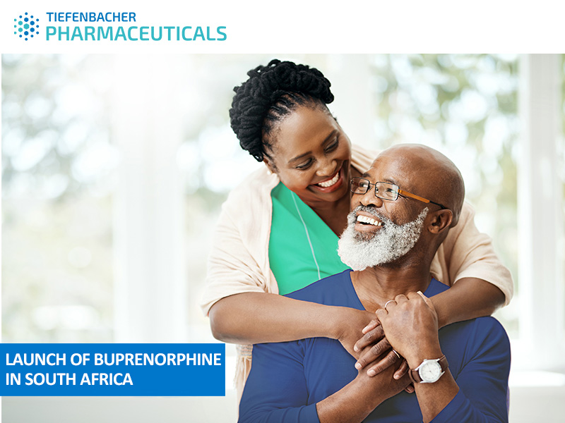 Tiefenbacher Group - A smiling older man with a gray beard sits while a woman stands behind him, hugging him. Text reads, "LAUNCH OF BUPRENORPHINE IN SOUTH AFRICA." The TIEFENBACHER PHARMACEUTICALS logo is at the top, highlighting expertise in generic medicines manufacturing.