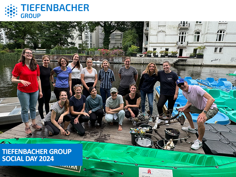 Tiefenbacher Group - A group from the family-owned pharmaceutical company Tiefenbacher Group smile and pose by a canal with pedal boats, enjoying their Social Day 2024 outdoors on a wooden dock.